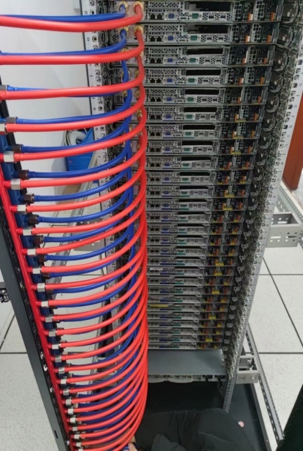 Server rack with red and blue liquid cooling pipes connecting each server